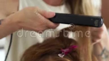 发型师用发钳做卷发。 在美容工作室里用发铁把卷曲的长发合上。 美容师